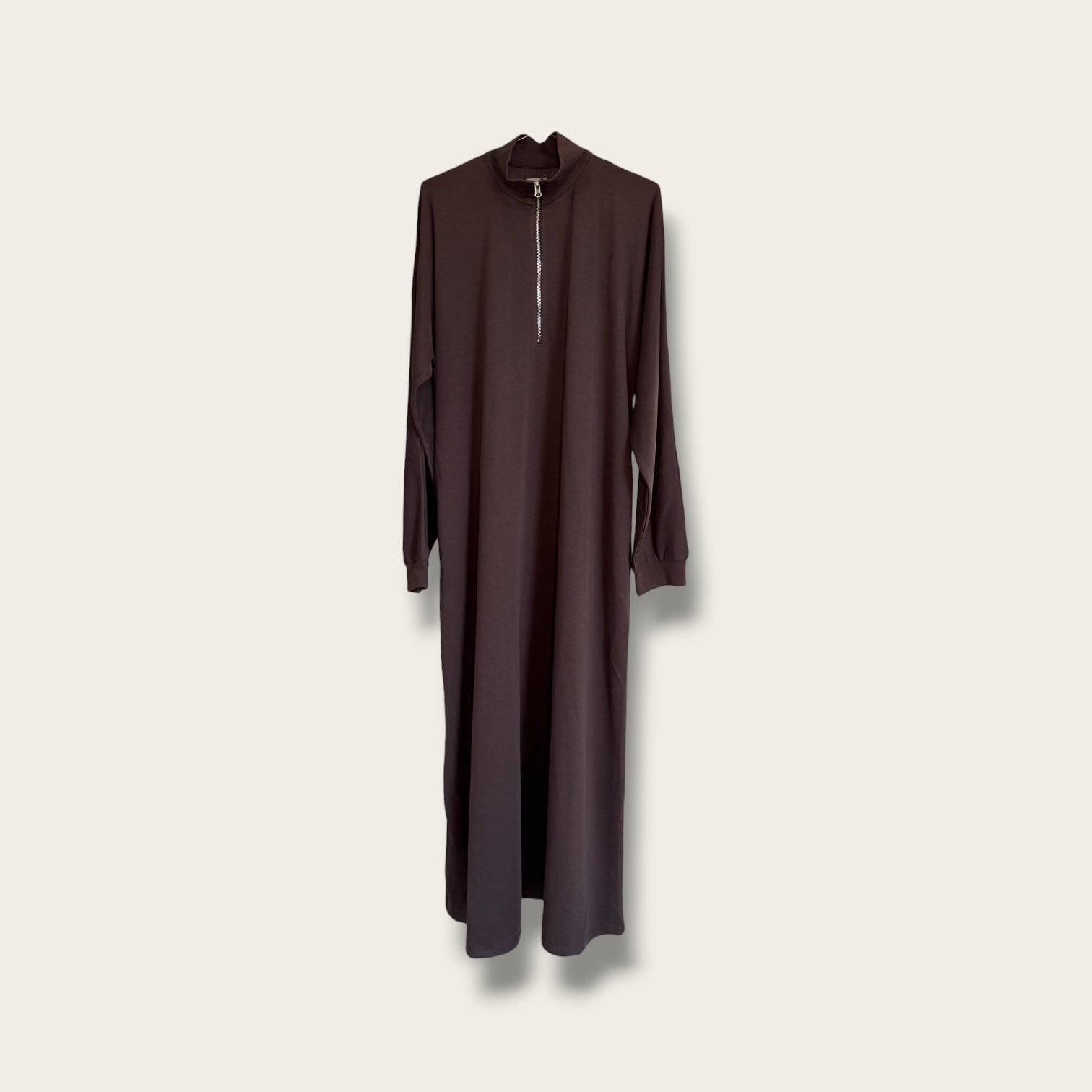 A long-sleeve, high-neck, maxi-length dress in a deep dark brown or plum-brown color, featuring a medium center zipper, shown hanging against a light beige background.